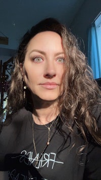 a woman with long curly hair wearing a black t - shirt